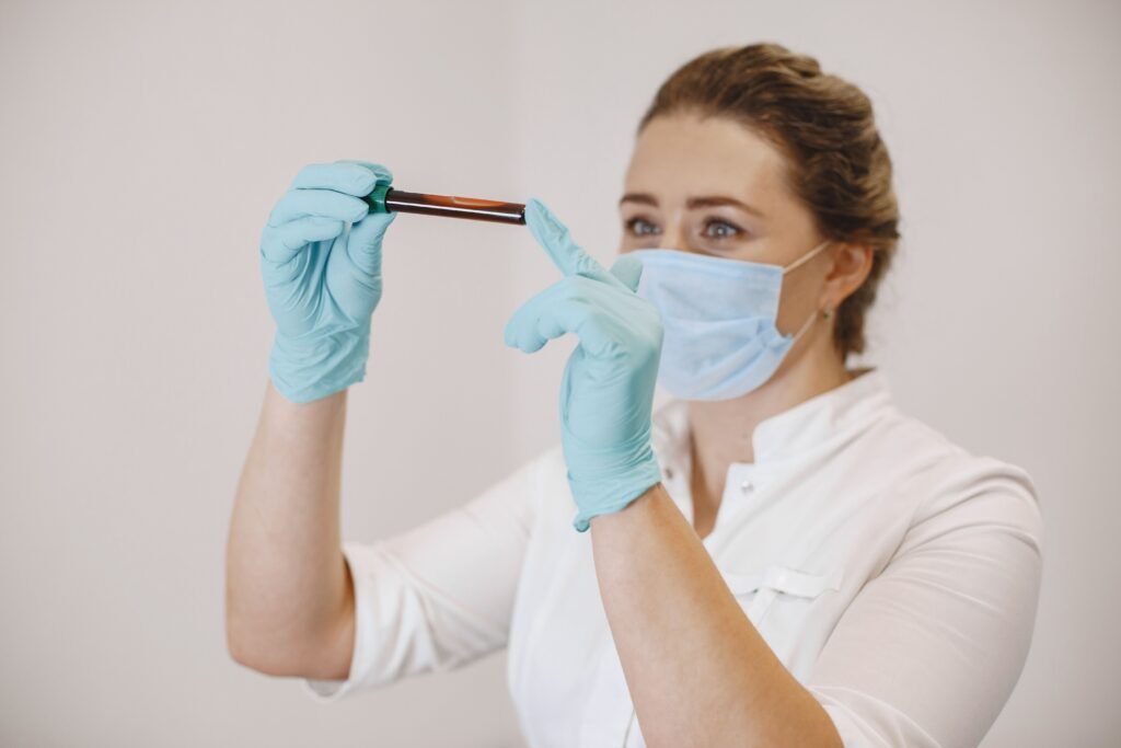 Female Infertility Testing Package (FITP) A female healthcare worker wearing gloves and a mask examines a blood sample in a test tube.