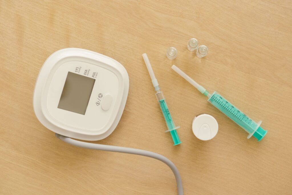 DIABETES CHECKUP/SCREENING PACKAGES Flat lay of medical equipment including a sphygmomanometer and syringes on a wooden surface.